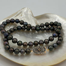 Load image into Gallery viewer, This glamourous Black Freshwater pearl strand features dark round pearls with Green and Purple hues, 8-8.5mm in size.
The highlight is the intricate goddess like Rose Gold and Sterling silver clasp that is a feature of this strand and designed to be worn to see.
Total length including clasp is 48cm