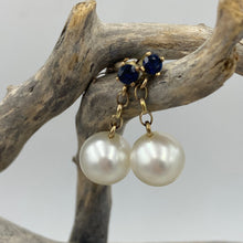 Load image into Gallery viewer, Stunning handcrafted 9ct yellow gold earrings featuring studs of Blue sapphires, 4mm round and claw set. Under this is 9ct chain joining to our highest grade White South Sea Pearls. They are 11.4mm, Round in shape White with pink hues, AAA grade lustre and skin