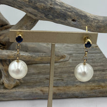 Load image into Gallery viewer, Stunning handcrafted 9ct yellow gold earrings featuring studs of Blue sapphires, 4mm round and claw set. Under this is 9ct chain joining to our highest grade White South Sea Pearls. They are 11.4mm, Round in shape White with pink hues, AAA grade lustre and skin