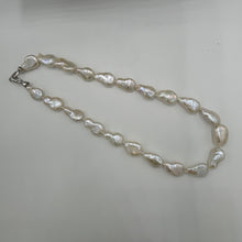 Load image into Gallery viewer, This gorgeous seedless pearl strand looks a little like pear shapes. It features white with high lustre, 12 x 20mm pearls that have no nuclei so are quite flat in shape. They sit perfectly on any neck. This strand is fully knotted and features a rhodium coated non tarnish Sterling silver clasp. The length including clasp is 44cm.