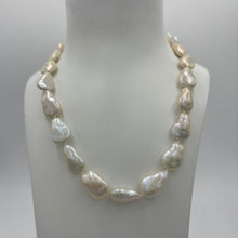 Load image into Gallery viewer, This gorgeous seedless pearl strand looks a little like pear shapes. It features white with high lustre, 12 x 20mm pearls that have no nuclei so are quite flat in shape. They sit perfectly on any neck. This strand is fully knotted and features a rhodium coated non tarnish Sterling silver clasp. The length including clasp is 44cm.