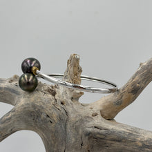 Load image into Gallery viewer, This double pearl bangle is unique with its Sterling Silver bangle featuring a gold plated rib at each pearl. The pearls are Round in shape, 11mm in size and are a natural unique Aubergine in color. They both have Good lustre.
It is featured on this non tarnish wrap bangle
J3515