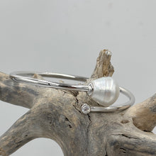 Load image into Gallery viewer, Sterling Silver solid bangle featuring an Australian South Sea Pearl and a bezel set cubic zirconia at either end
This stunning pearl is an Australian South Sea pearl, Circle Drop in shape and 13.8 x 15mm in size. It has high lustre and light natural birthmarks
It is White with Silver Pink hues and is featured on this non tarnish wrap bangle
J3508