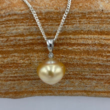 Load image into Gallery viewer, This Golden South Sea pearl pendant is set on 925 Sterling silver with a single bezel set cubic zirconia for subtle bling. The setting has a non tarnish finish.
The pearl is Button in shape, 11mm in size and a warm deep gold colour.
The lustre is Good with some light 'birthmarks'
Chain included is Base metal only
J3231