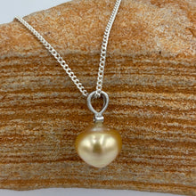 Load image into Gallery viewer, This Golden South Sea pearl pendant is set on 925 Sterling silver with a single bezel set cubic zirconia for subtle bling. The setting has a non tarnish finish.
The pearl is Button in shape, 11mm in size and a warm deep gold colour.
The lustre is Good with some light 'birthmarks'
Chain included is Base metal only
J3231