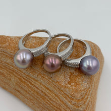 Load image into Gallery viewer, This exquisite ring features a superb Round 11.5 to 12mm Edison Freshwater pearl that is a stunning deep natural colour.
It is just divine with baget cut white cubic zirconia set along both shoulders of this 925 Sterling Silver, non tarnish finish ring
The size is adjustable and there are three colors to choose from Lavender, Chocolate and Blue as seen in the photo below
Size is adjustable