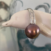 Load image into Gallery viewer, There is only one of these and the size is adjustable.
This exquisite ring features a superb Round 12mm Freshwater pearl that is a natural Chocolate color with Gold hues.
It is just divine with baget cut white cubic zirconia set along both shoulders of this 925 Sterling Silver, non tarnish finish ring
Size is adjustable