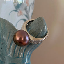 Load image into Gallery viewer, There is only one of these and the size is adjustable.
This exquisite ring features a superb Round 12mm Freshwater pearl that is a natural Chocolate color with Gold hues.
It is just divine with baget cut white cubic zirconia set along both shoulders of this 925 Sterling Silver, non tarnish finish ring
Size is adjustable