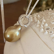 Load image into Gallery viewer, This Fijian South Sea pearl pendant enhancer is set on 925 Sterling silver with four channel set cubic zirconia for added bling. The setting has a non tarnish finish.
It is quite rare for a Blacklip pearl oyster to produce a gold pearl but in the waters of Fiji anything is possible due to the mix of coral and estuaries. This pearl is deep Gold with a green hue in colour, and is Semi Baroque in shape. The size of this unique pearl is 10.5 x 14mm.
The lustre is Excellent and the birthmarks