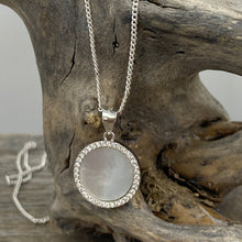 Load image into Gallery viewer, 'Nola' is a delicate sterling silver pendant featuring a Mother of Pearl disc surrounded by a ring of sparkling cubic zirconia. creating a soft, elegant look.
Total width is 15mm
Chain is base metal only
There is a matching pair of earrings and ring by the same name