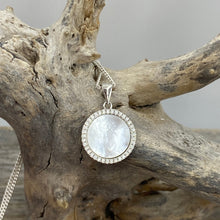 Load image into Gallery viewer, 'Nola' is a delicate sterling silver pendant featuring a Mother of Pearl disc surrounded by a ring of sparkling cubic zirconia. creating a soft, elegant look.
Total width is 15mm
Chain is base metal only
There is a matching pair of earrings and ring by the same name