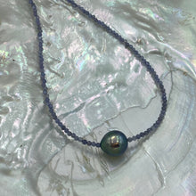 Load image into Gallery viewer, Tahitian pearl necklace with faceted Tanzanite gemstones and a sterling silver peanut clasp. This necklace features a peacock coloured Tahitian pearl, drop shape, and 9.5mm x 10.5mm in size. It is white with silver hues in colour. Good lustre and light natural 'birthmarks'. Beautiful 2mm Tanzanite and the overall length, including clasp, is 45cm. J3373