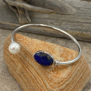 This bangle is a colorful addition to any collection featuring a facetted blue Lapis gemstone and a white Freshwater pearl, Button in shape and 10mm in size

It is made from 925 sterling silver and has a non tarnish finish and is an adjustable size