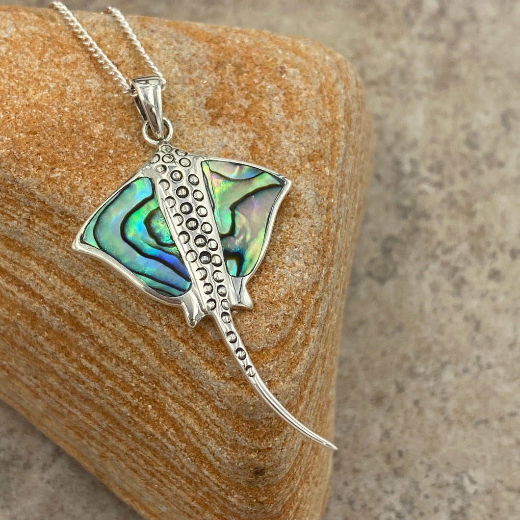 Sterling Silver Pendant features green blue NZ Paua  shell in the shape of a Manta Ray and textured up the middle.

It is 25mm across and 50mm from top to bottom of the tail

Price includes Base Metal chain.