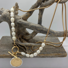 Load image into Gallery viewer, This necklace features a coin pendant on a long chain, complemented by radiant freshwater pearls on either side for a sophisticated and timeless look. This elegant design combines classic luxury with a modern twist.

Pearls measure approx. 8mm.

Total length of necklace is 85cm.
