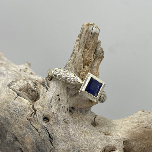 This classic style ring is 925 sterling silver and  features a rectangle shaped bezel set synthetic blue sapphire in the centre (6.5 x 8mm including bezel) and grain set cubic zirconia along the band 



It is size L1/2

IR14