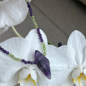 This earthy necklace features 3.5mm facetted Amethyst and Peridot gemstone beads , with a large rough cut Amethyst as the centre feature  It has a 925 sterling silver peanut clasp.  It is on 49 strand high strength US wire with scrimps for security  The overall length including clasp is  45cm 