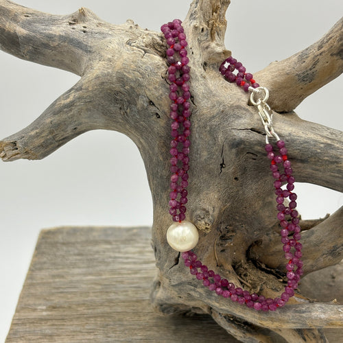 Freshwater pearl bracelet with 2mm faceted ruby gemstones and a sterling silver lobster clasp  This stunning pink ruby bracelet has been woven to create a lace like effect  It is 20cm in overall length and features a single Freshwater pearl, off round, and 8.8mm in size