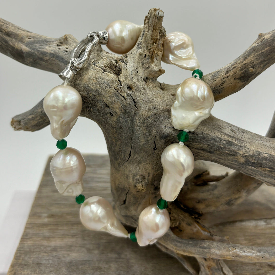 This stunning baroque Freshwater pearl bracelet features Eight High lustre pearls, 13 x 21mm in size and  white in colour.  These pearls are highlighted between each pearl with a facetted 4mm Green  Onyx gemstones.  It has a rhodium coated non tarnish 925 Sterling Silver clasp.  The length including clasp is 22cm.