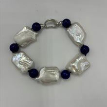 Load image into Gallery viewer, This rectangular shaped seedless Freshwater pearl bracelet features Five high lustre pearls, 18 x 22mm in size, stunning white in colour and highlighted with six beautiful 10mm Blue Lapis beads.  It features a 925 Sterling Silver clasp and is fully knotted.  The length including clasp is 21cm.
