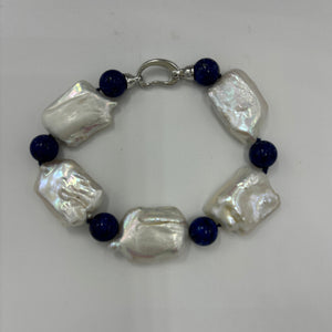 This rectangular shaped seedless Freshwater pearl bracelet features Five high lustre pearls, 18 x 22mm in size, stunning white in colour and highlighted with six beautiful 10mm Blue Lapis beads.  It features a 925 Sterling Silver clasp and is fully knotted.  The length including clasp is 21cm.