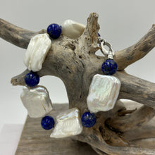 Load image into Gallery viewer, This rectangular shaped seedless Freshwater pearl bracelet features Five high lustre pearls, 18 x 22mm in size, stunning white in colour and highlighted with six beautiful 10mm Blue Lapis beads.  It features a 925 Sterling Silver clasp and is fully knotted.  The length including clasp is 21cm.
