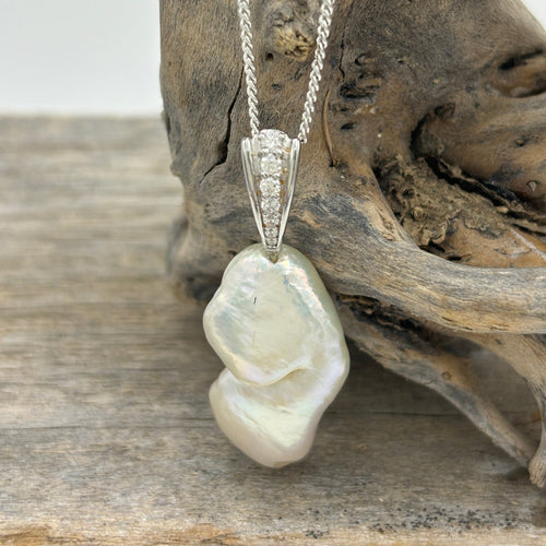 This unique pendant features a striking setting embellished with cubic zirconia.  The pearl is a unique natural shape seedless 'keshi' freshwater pearl that is white with high lustre. It is 15.5 x 28mm in size.