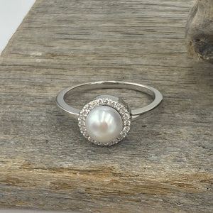 Sterling silver ring featuring an 7.5mm White freshwater&nbsp; Button shape pearl cradled inside a circle of Cubic Zirconia.

This ring has a non tarnish finish and comes in various sizes