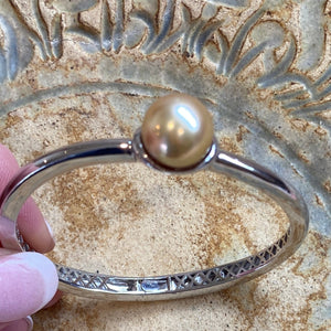 Sterling Silver solid bangle featuring an Indonesian South Sea Pearl  This stunning  pearl  is an Australian South Sea pearl,  Button in shape and 12.7mm in size. It is Deep Gold in color with High lustre and is featured on this rhodiun coated non tarnish bangle   J3294