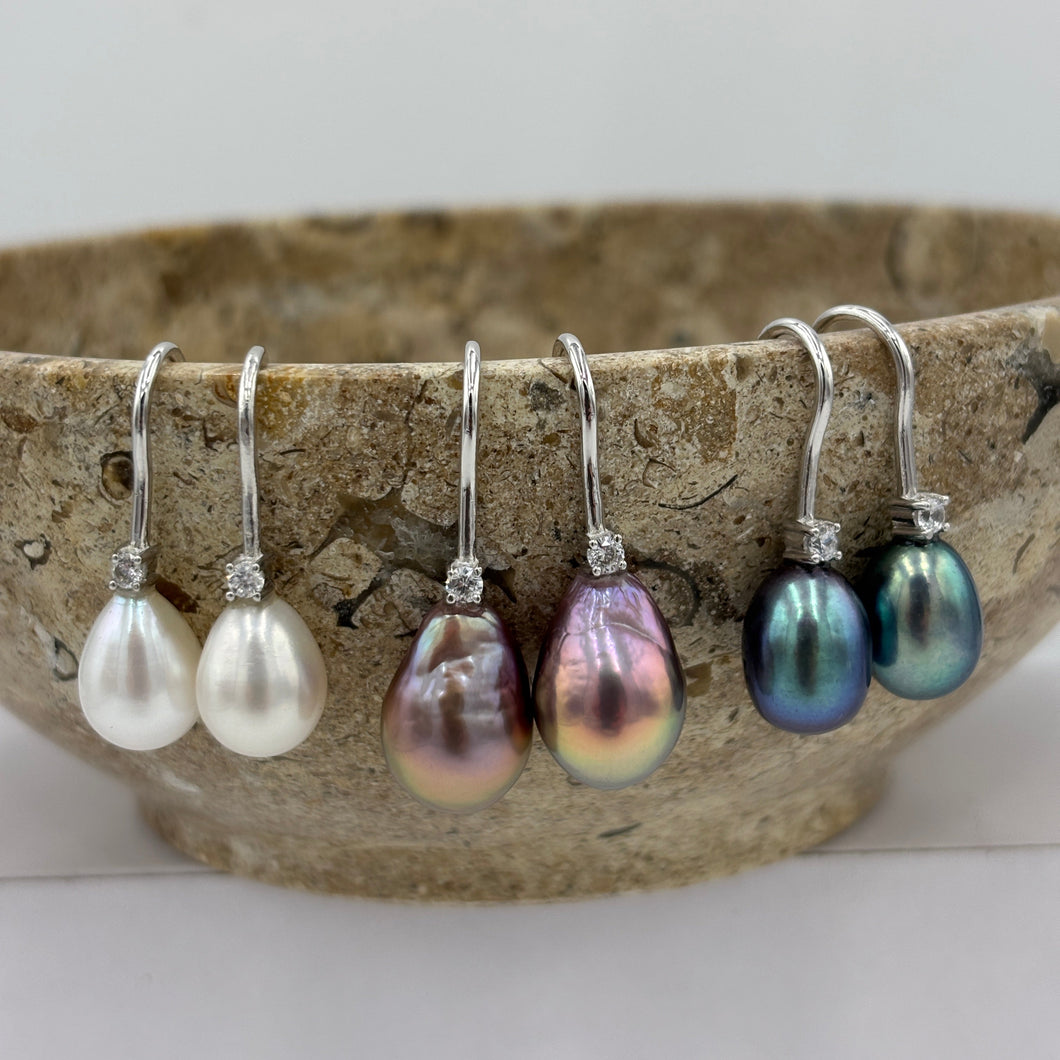 These elegant and classic Hook earrings are Sterling Silver and rhodium coated for a non tarnish finish and they feature a single claw set cubic zirconia above each pearl.

The pearls are tear drop shape, 9 x 12mm in size and white with pink hues in colour.

Also available with Black or Pink pearls to order
