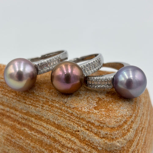 This exquisite ring features a superb Round 11.5 to 12mm Edison Freshwater pearl that is a stunning deep natural colour.

It is just divine with baget cut white cubic zirconia set along both shoulders of this 925 Sterling Silver, non tarnish finish ring

The size is adjustable and there are three colors to choose from Lavender, Chocolate and Blue as seen in the photo below

Size is adjustable