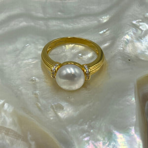 This elegant and feminine ring features a single white Button 9.5mm freshwater pearl   It is 18k gold plated over 925 Sterling silver and features pave set cubic zirconia on either side of the pearl  Sizes available to select from 