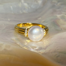 Load image into Gallery viewer, This elegant and feminine ring features a single white Button 9.5mm freshwater pearl   It is 18k gold plated over 925 Sterling silver and features pave set cubic zirconia on either side of the pearl  Sizes available to select from 
