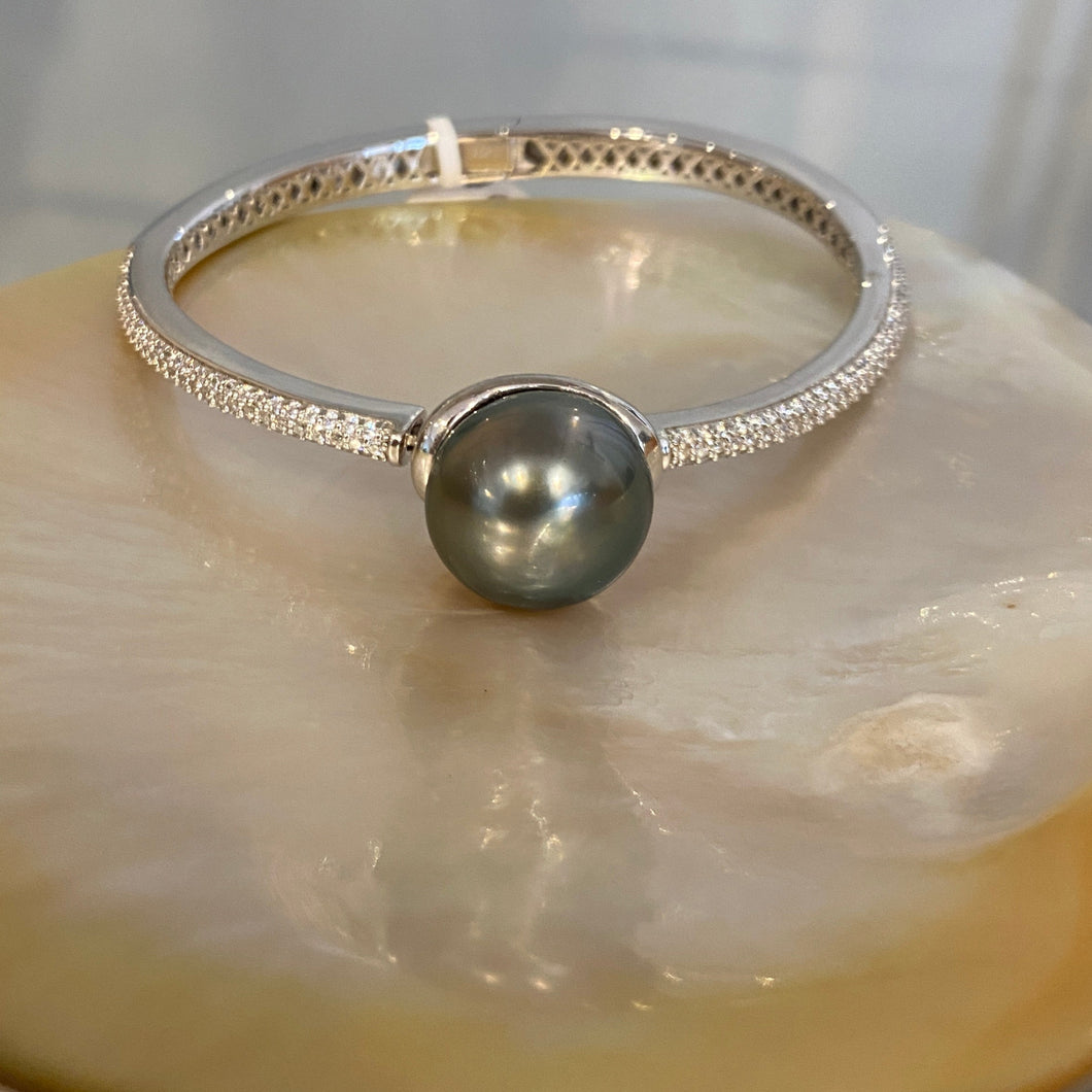 Sterling Silver solid bangle featuring a Tahitian South Sea Pearl

This stunning  pearl  is Tahitian and is Button in shape and 15mm in size.

It is Dark Green with Aubergine hues with High lustre and is featured on this rhodiun coated non tarnish bangle covered with pave set cubic zirconia 

J3292