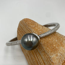 Load image into Gallery viewer, Sterling Silver solid bangle featuring a Tahitian South Sea Pearl

This stunning&nbsp; pearl&nbsp; is Tahitian and is Button in shape and 15mm in size.

It is Dark Green with Aubergine hues with High lustre and is featured on this rhodiun coated non tarnish bangle covered with pave set cubic zirconia&nbsp;

J3292
