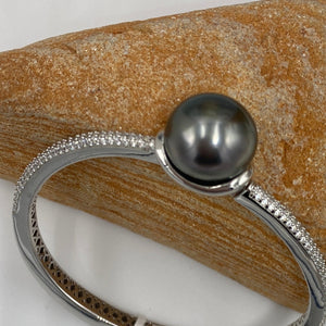 Sterling Silver solid bangle featuring a Tahitian South Sea Pearl

This stunning&nbsp; pearl&nbsp; is Tahitian and is Button in shape and 15mm in size.

It is Dark Green with Aubergine hues with High lustre and is featured on this rhodiun coated non tarnish bangle covered with pave set cubic zirconia&nbsp;

J3292