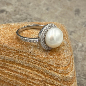 Stunning Sterling silver ring featuring an 11mm White freshwater&nbsp; Button shape pearl cradled in a Halo of&nbsp; Cubic Zirconia which also extend down the shank of the ring.

This ring has a non tarnish finish and comes in various sizes