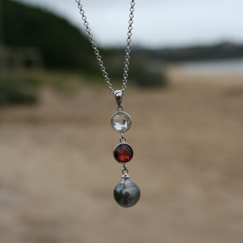 This pendant features an 8mm facetted garnet, clear quartz and a Tahitian South Sea Pearl. The pearl is  Drop in shape and 10.1mm in size and a Pale Peacock Green with pink hues in color. It is crafted from 925 Sterling silver  J3258