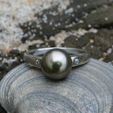 Load image into Gallery viewer, This stunning 925 sterling silver ring features a Semi Round Tahitian pearl, 9.2mm in size and Green with Aubergine tones in color. It has high lustre and glows  This ring design features two cubic zirconia one on either side of the pearl  It is rhodium coated 925 Sterling silver so will not tarnish   Size 56  J2932
